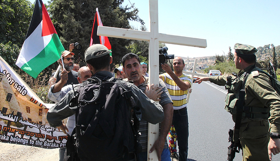 Palestinian, Israeli and Christian foreign activists confront Israeli soldiers as they walk toward Beit al-Baraka, a church compound, situated between the Al-Arub refugee camp and the city of Hebron in the occupied West Bank during a demonstration condemning the Israeli occupation, Aug. 15, 2015.  (photo by Getty Images/Hazem Bader)